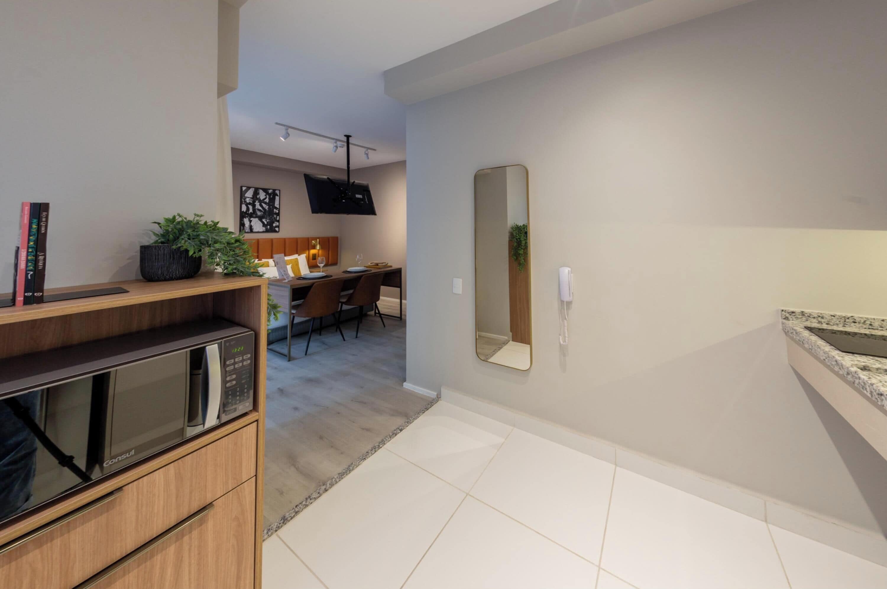 A modern kitchen with a microwave, a wooden cabinet, and a dining area with chairs and a table.