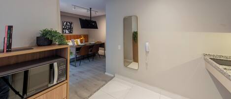 A modern kitchen with a microwave, a wooden cabinet, and a dining area with chairs and a table.