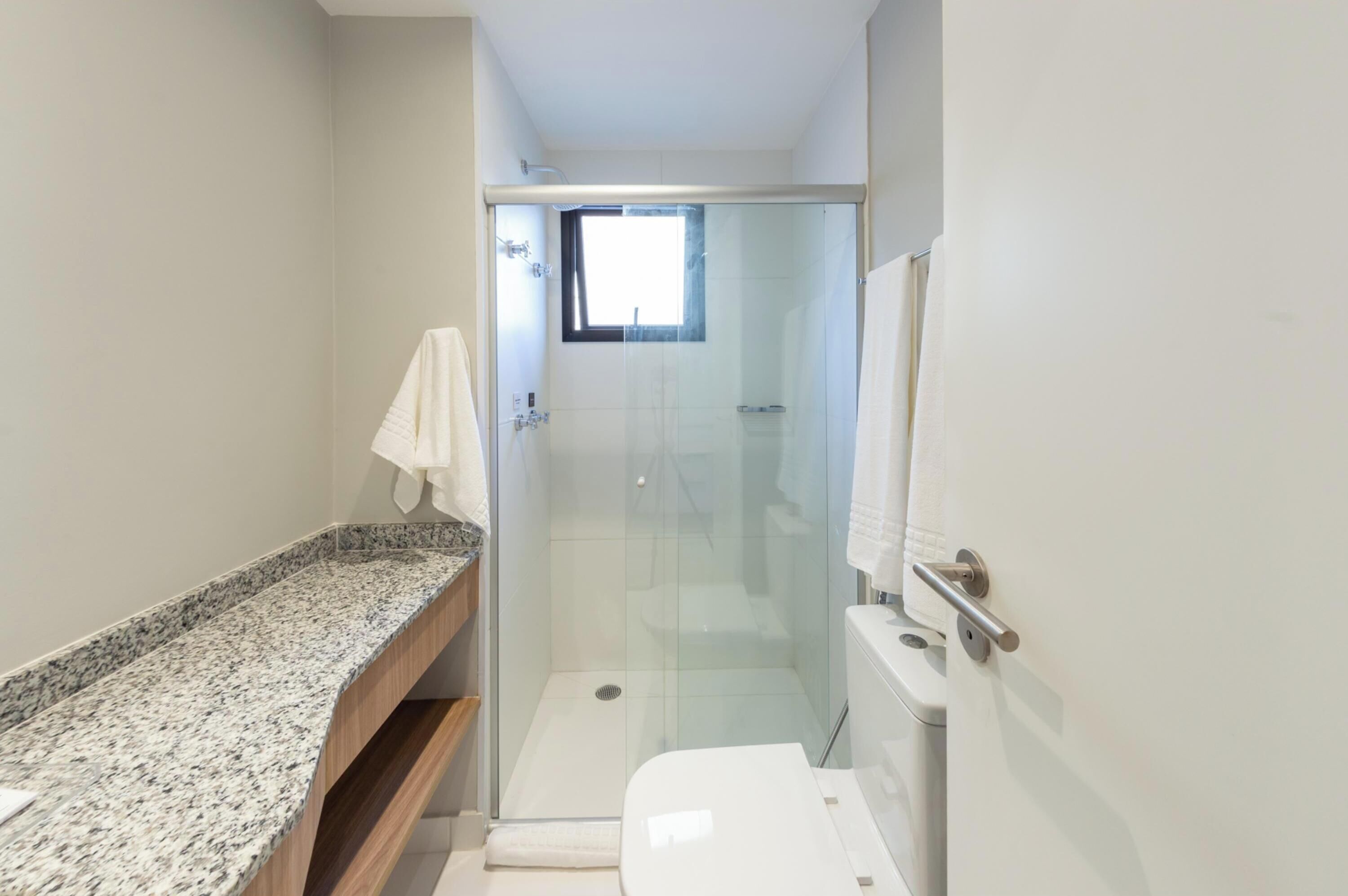 Une salle de bain avec douche, toilettes et comptoir en granit.