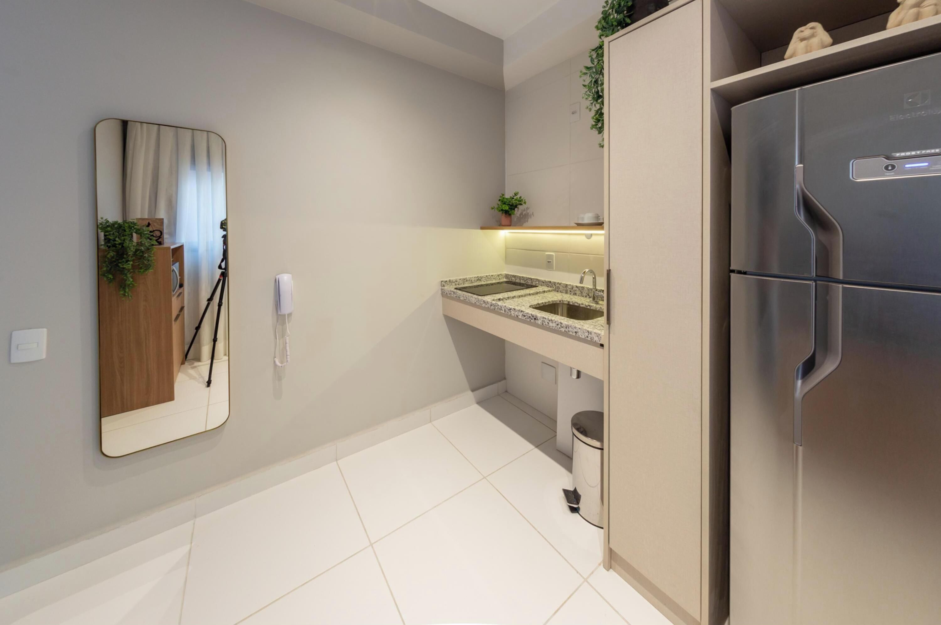 Une cuisine moderne dotée d’un réfrigérateur encastré, d’un évier à deux bacs et d’un miroir mural.