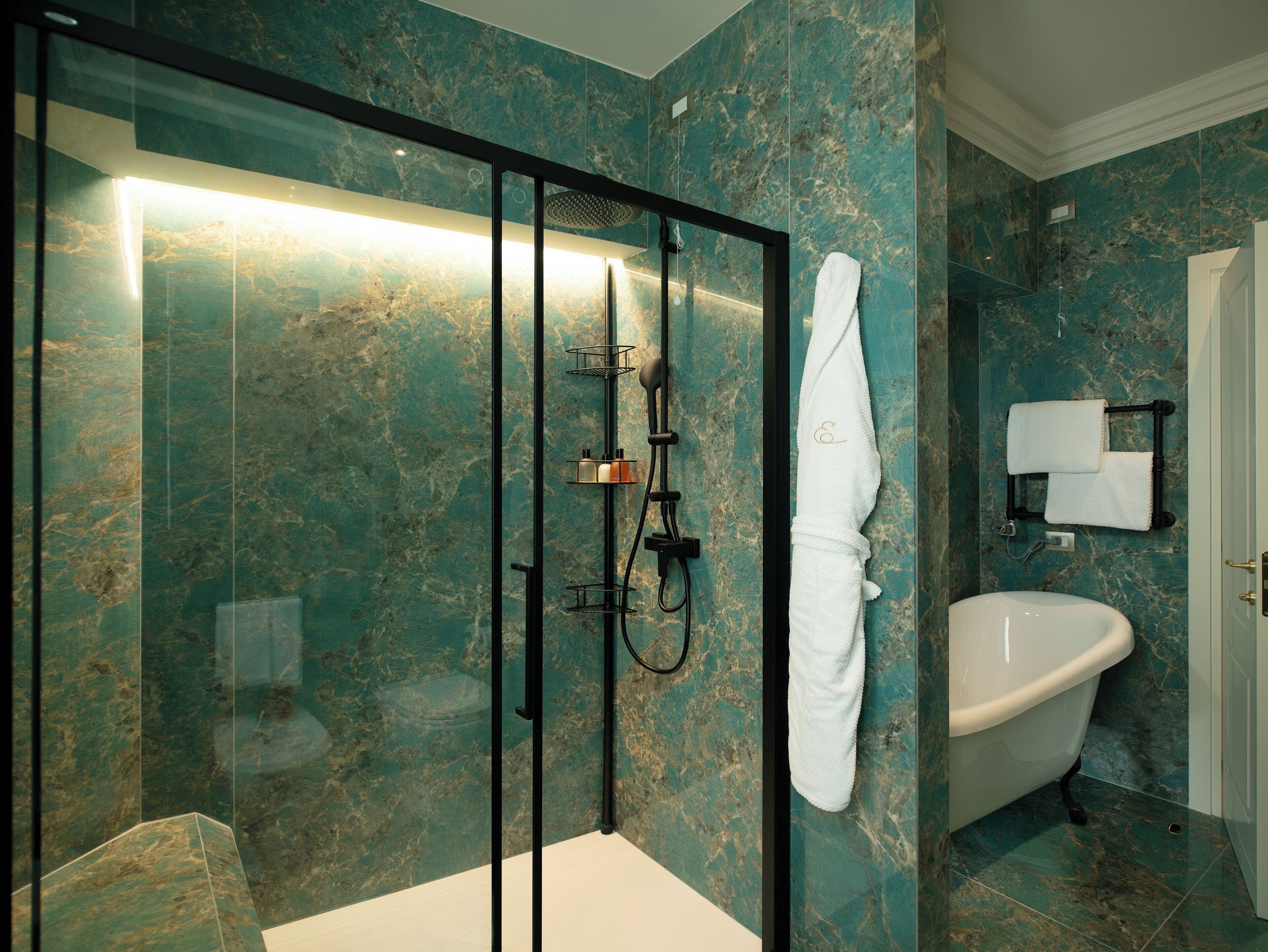 Un baño moderno con ducha acristalada, una bañera blanca y pared de mármol.