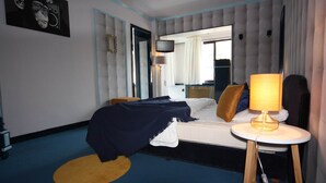 A hotel room with a bed, a TV, a lamp, and a mirror.