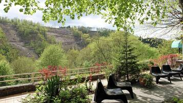 Een terras met uitzicht op een vallei, buitenmeubels en een balustrade.