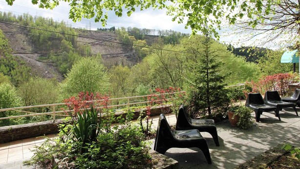 A terrace with a view of a valley, outdoor seating, and a railing.