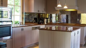 A modern kitchen with a central island, stainless steel appliances, and a large window providing natural light. - Peer Villa with Garden (Peer)
