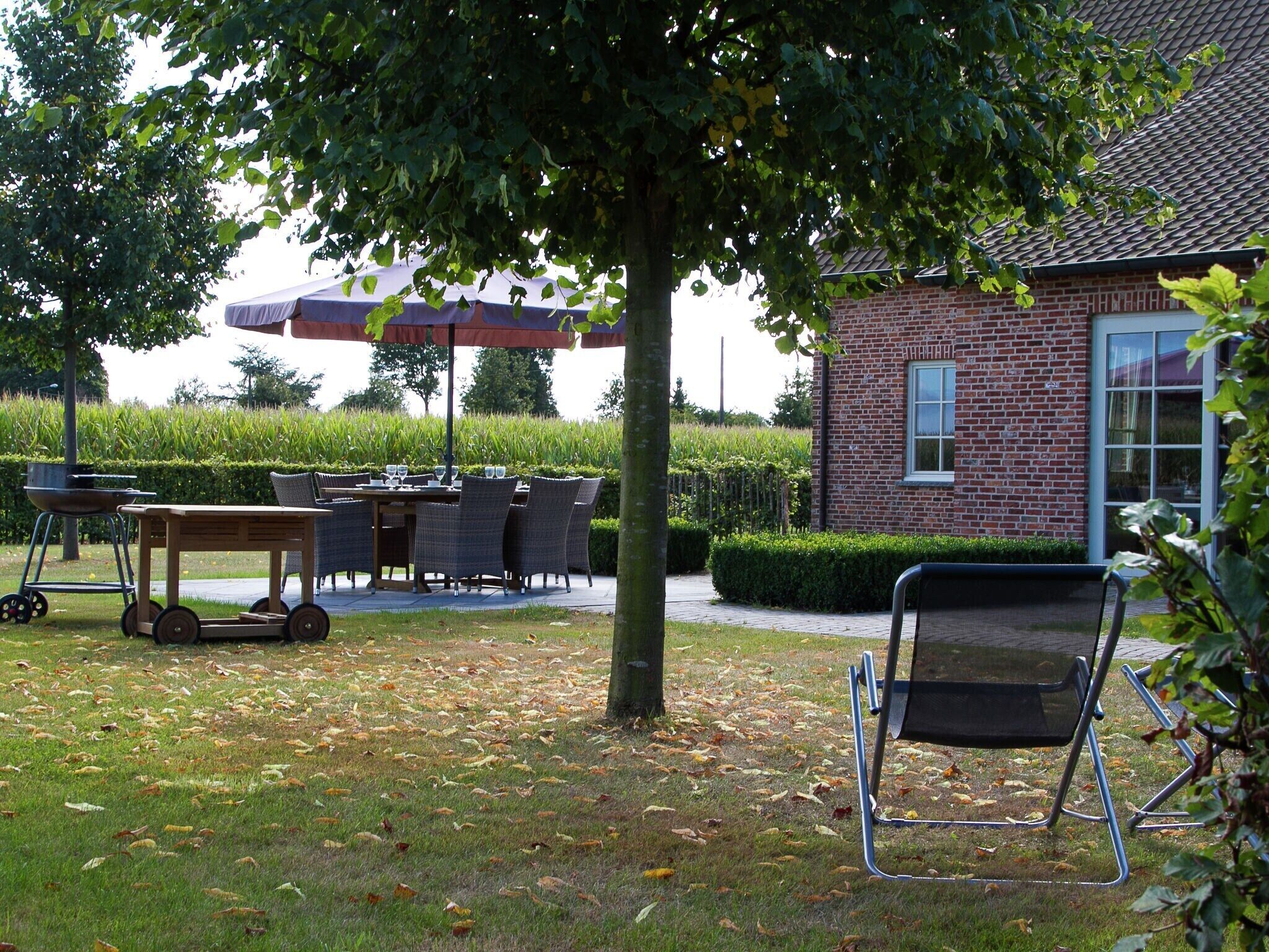 Un patio con mobiliario exterior, una mesa y una parrilla.
