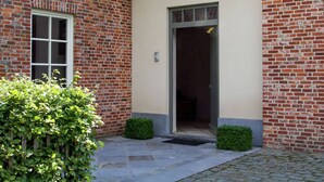 A brick building with a beige facade, a large window, and a door. - Peer Villa with Garden (Peer)