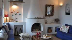 Un salon chaleureux avec une cheminée, des canapés bleus, une table agrémentée d’objets décoratifs et un miroir fixé au mur.