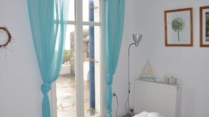 Une pièce comprenant un lit, un radiateur, une fenêtre avec des rideaux, une lampe fixée au mur et des tableaux encadrés.