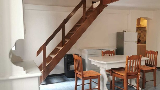Un'area pranzo con una scala in legno, un tavolo bianco e sedie.