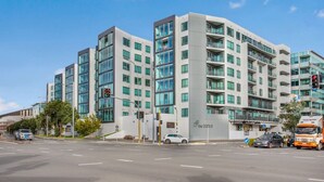 A modern multi-story building with large windows, a flat facade, and a visible entrance. - Quayside Quarters Apt close to Spark Arena (Auckland CBD)