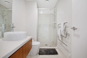 Une salle de bain moderne avec un lavabo blanc, des toilettes et une douche à parois de verre.