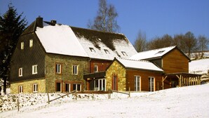 A large, multi-story building with stone and wooden exteriors, multiple windows, and a snow-covered roof. - Wellness & Wilderness: Libômont Escape (Waimes)