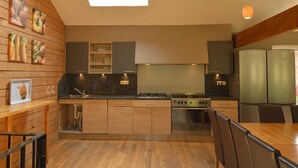 A modern kitchen with wooden cabinetry, a gas stove, and a built-in oven. - Wellness & Wilderness: Libômont Escape (Waimes)