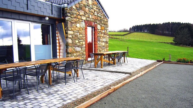 An outdoor seating area with stone walls and a view of a green field. - Wellness & Wilderness: Libômont Escape (Waimes)