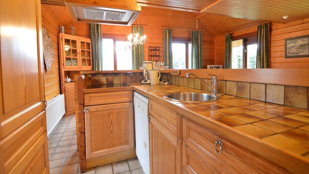 Une cuisine rustique, aménagée dans une cabane en bois, avec un évier, des placards et une cuisinière.