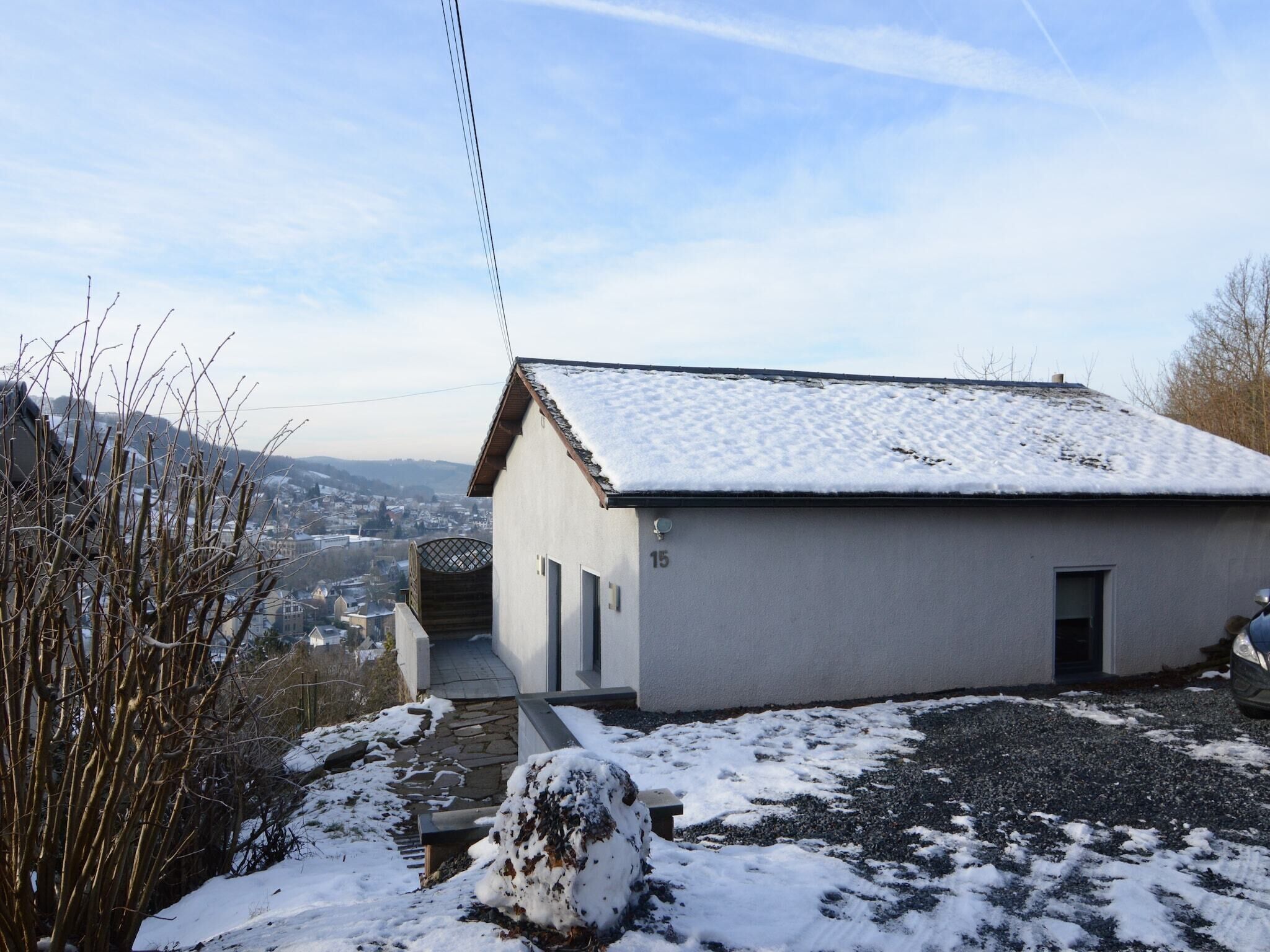 Un edificio pequeño de un solo piso con techo cubierto de nieve y un sendero de piedra que lleva a la entrada.