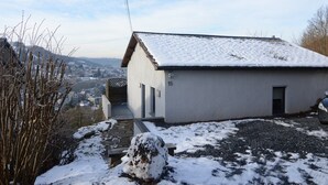 Um pequeno edifício térreo com telhado coberto de neve e um caminho de pedra que leva à entrada.