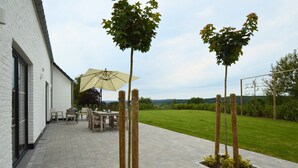 A patio area with a table and chairs, a large umbrella, and two trees. - Forestside Retreat, Malmedy (Malmedy)