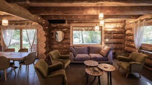 Acogedor interior de cabaña de madera con comedor, sofá y sillones.