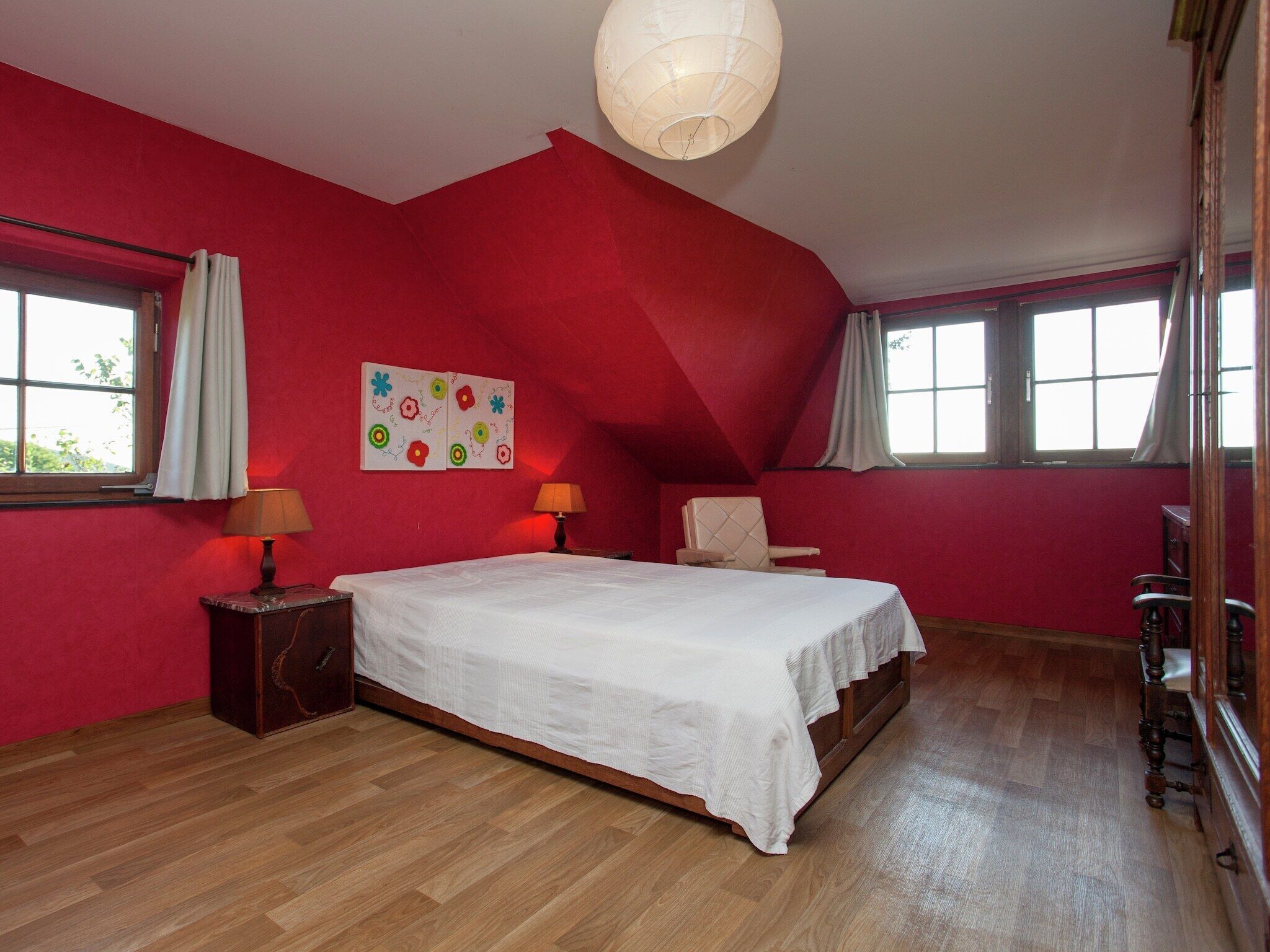 A bedroom with a large bed, two bedside tables, a chair, and a ceiling light fixture.