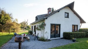 A white house with a gravel driveway and a patio area with a table and chairs.