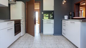 A compact kitchen with white cabinets, a stainless steel range hood, and a microwave.