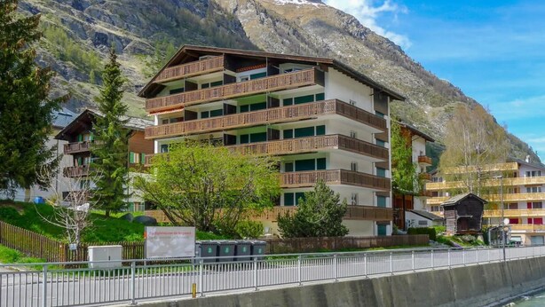 A multi-story hotel with balconies, set against a mountainous backdrop. - Haus Matten - Studio Findeln (Zermatt)