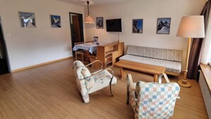 A living room with a sofa, a small table, a chair, and a TV. - Haus Matten - Studio Findeln (Zermatt)