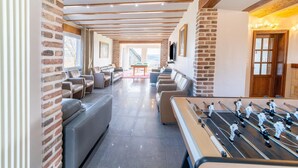 Une pièce spacieuse avec un baby-foot, des canapés en cuir et un mur en briques.
