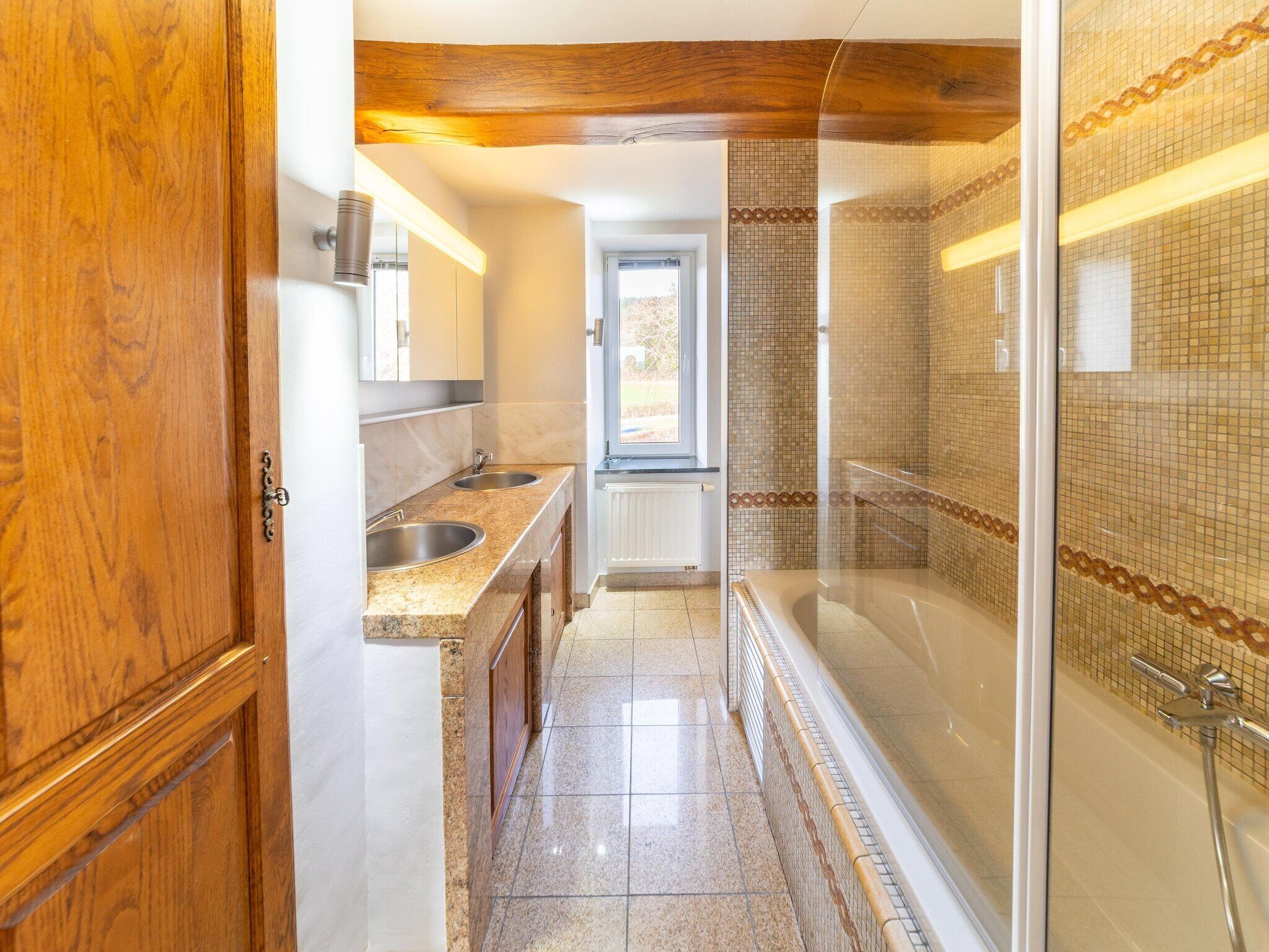 A modern bathroom with a shower, two sinks, and a window.