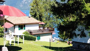 A house with a balcony overlooking a lake, surrounded by greenery and mountains. - Directly on the lake with terrace (Tre Capitelli)