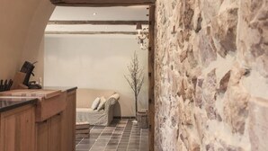 Une pièce chaleureuse avec un mur en pierre, un banc en bois et un canapé.