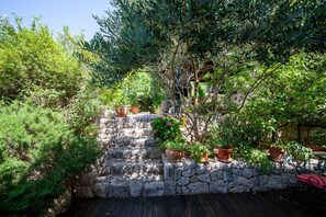 Relax on the deck surrounded by lush vegetation and a serene stone wall.