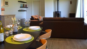 A dining area with a table set for two, a sofa, and a fireplace. - Family Apartment; Bouillon and Semois River (Gros-Fays)