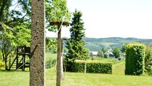 A rural landscape with a wooden structure, a rope swing, and a view of houses in the distance. - Family Apartment; Bouillon and Semois River (Gros-Fays)