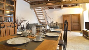 Ein Essbereich mit einem Holztisch, gedeckt für vier Personen, einer Treppe und einer Küchenzeile mit Holzschränken und einem Kühlschrank.
