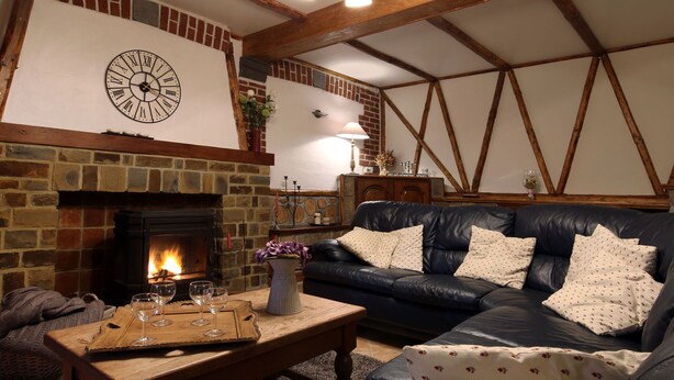 A cozy living room with a fireplace, leather sofa, and a clock on the wall. - Modern Spacious Holiday Home (Mettet (maison st Gérard))