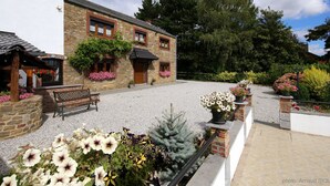 A stone building with a gravel courtyard, benches, and potted plants. - Modern Spacious Holiday Home (Mettet (maison st Gérard))