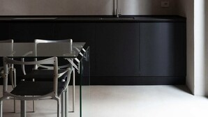A modern kitchen with a black countertop, stainless steel appliances, and a minimalist design. - Ho'c Suite (Milano)