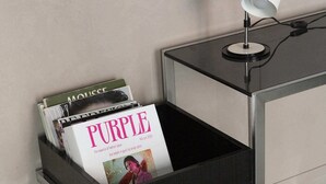 A black metal side table with a magazine holder containing a 'Purple' magazine and other magazines. - Ho'c Suite (Milano)