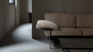 A minimalist living room with a sofa, a coffee table, and a window providing natural light. - Ho'c Suite (Milano)
