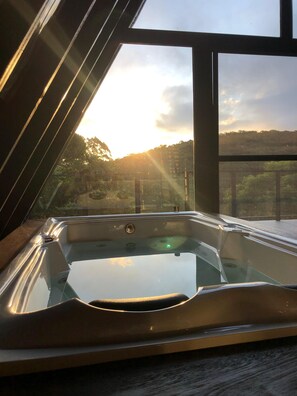 Un bain à remous offrant une vue d égagée sur le coucher de soleil et le paysage environnant, grâce à une grande fenêtre.