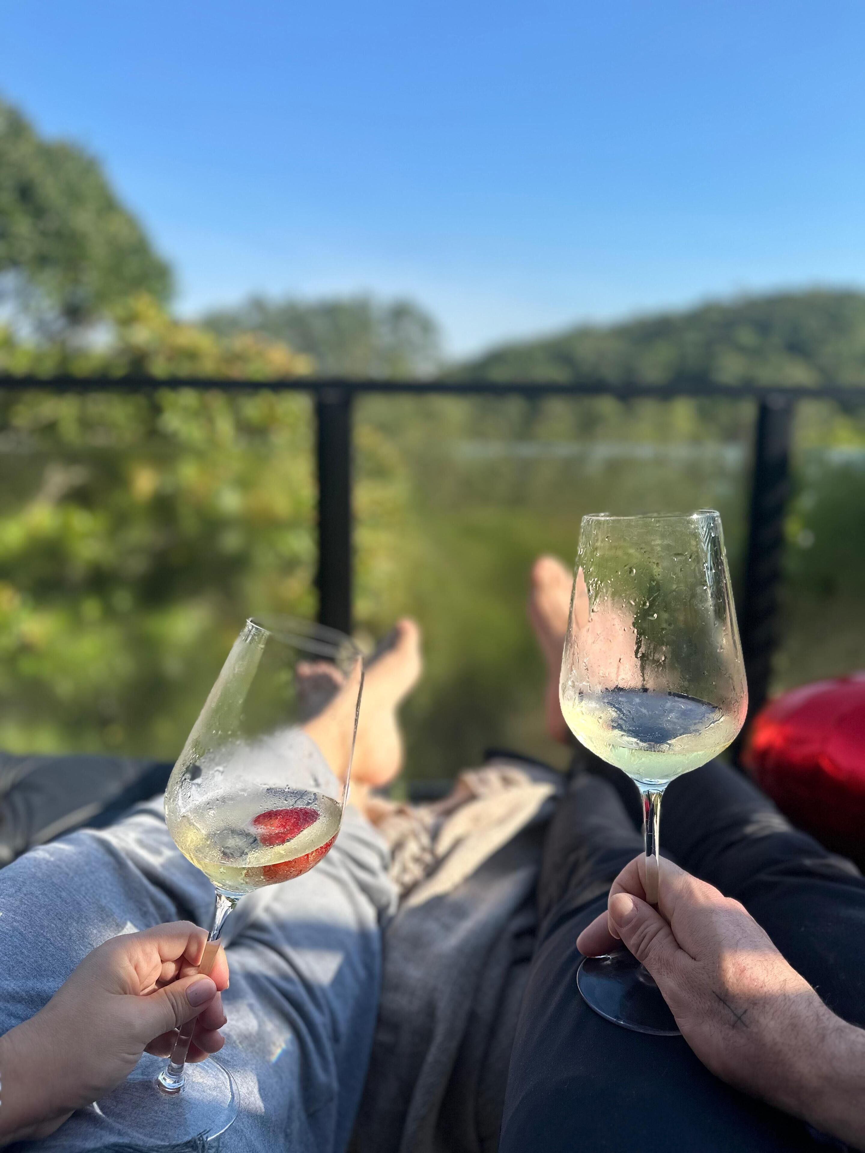 Two people reclining on a balcony with a clear view of a forested landscape.