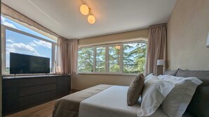A bedroom with a large bed, a TV on a stand, and a window with curtains. - Quarto di Monte Suite & Spa (Andria)
