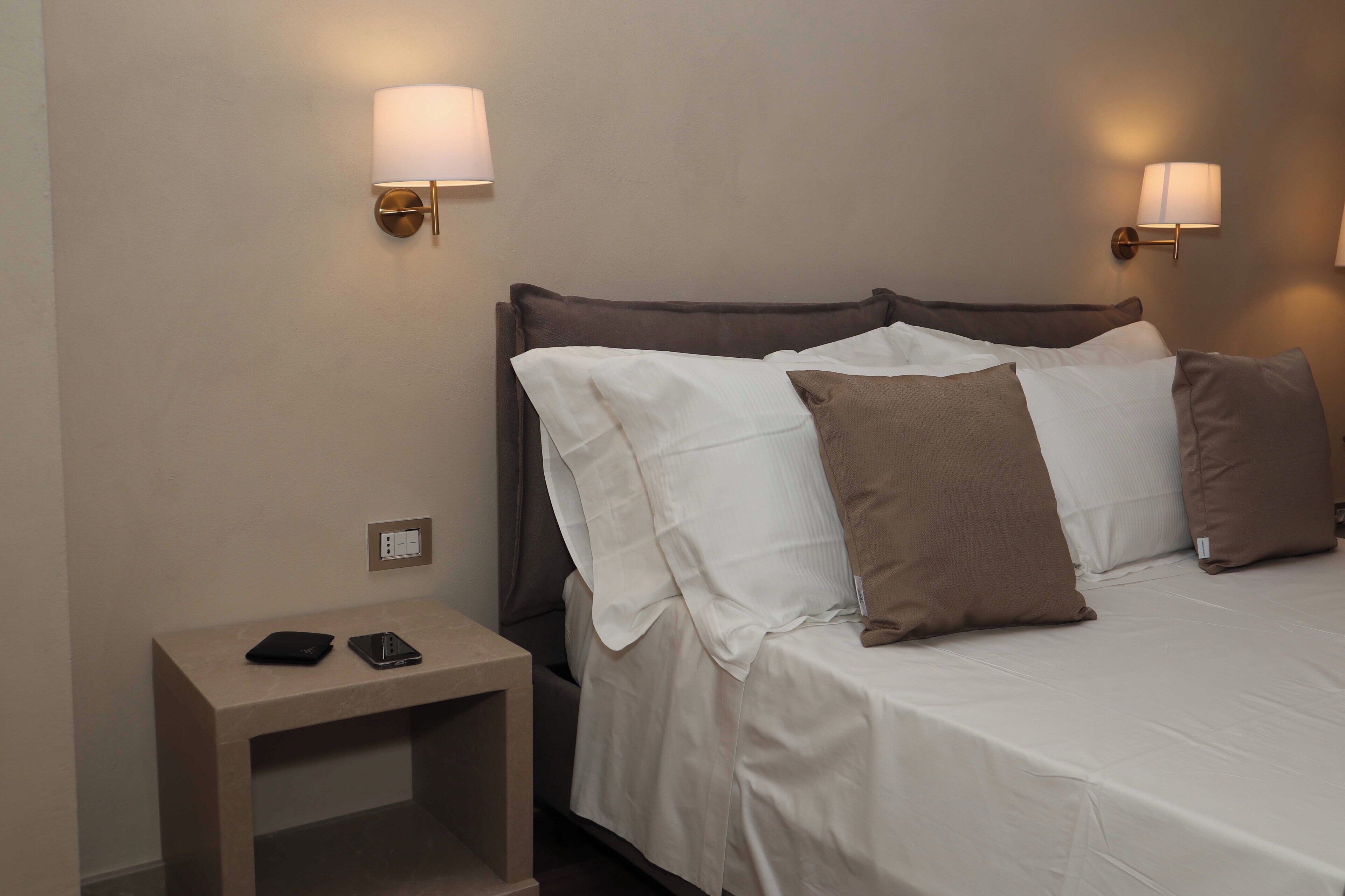 Una camera d'albergo con un letto, comodini e lampade a parete.