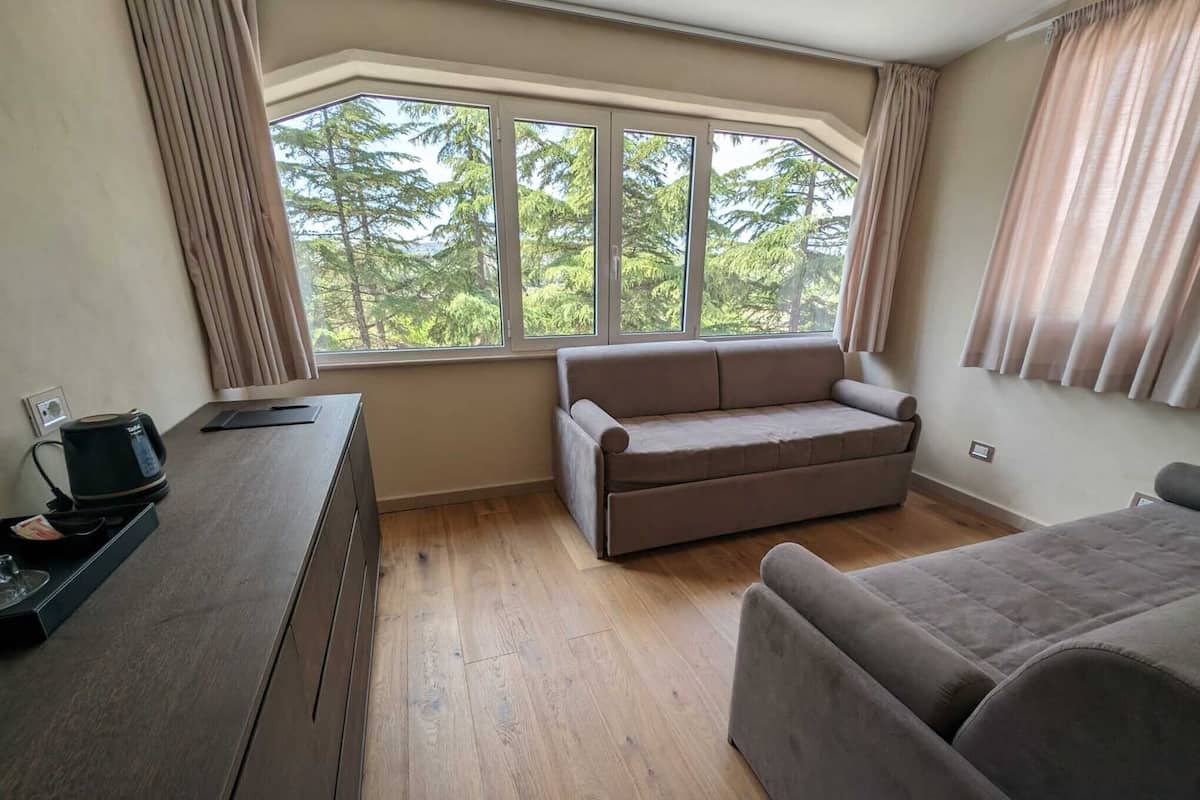 A room with a sofa, a wooden table, and a window with curtains.