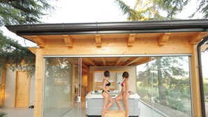 A modern glass-enclosed room with a hot tub and wooden beams. - Quarto di Monte Suite & Spa (Andria)