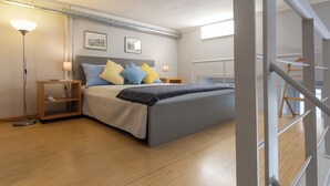 Un dormitorio moderno con cama, mesitas de noche, una lámpara de pie y una ventana.