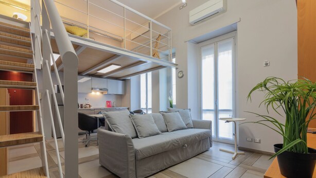 Un apartamento moderno con zona de estar tipo loft, comedor y escalera.